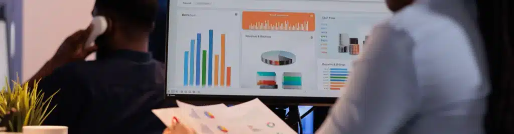 Business professionals reviewing financial dashboard with revenue charts and analytics on computer screen