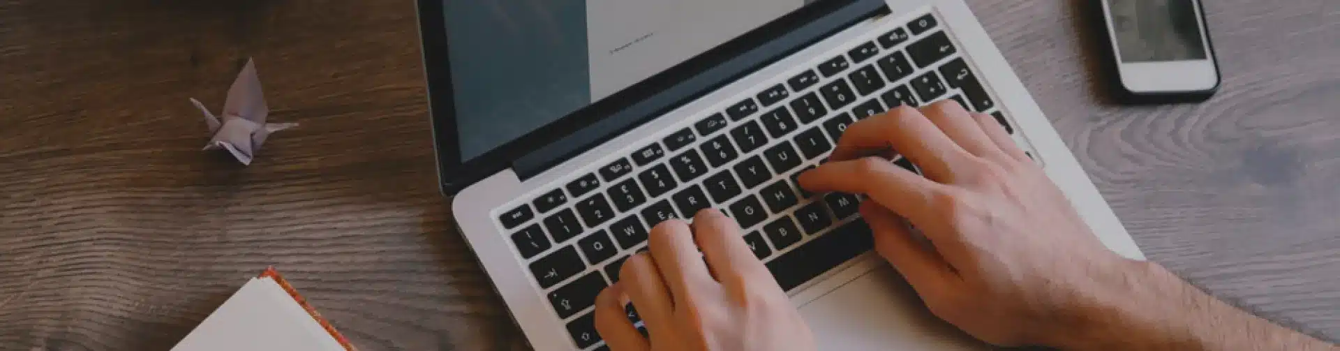 Person typing on laptop computer at wooden desk