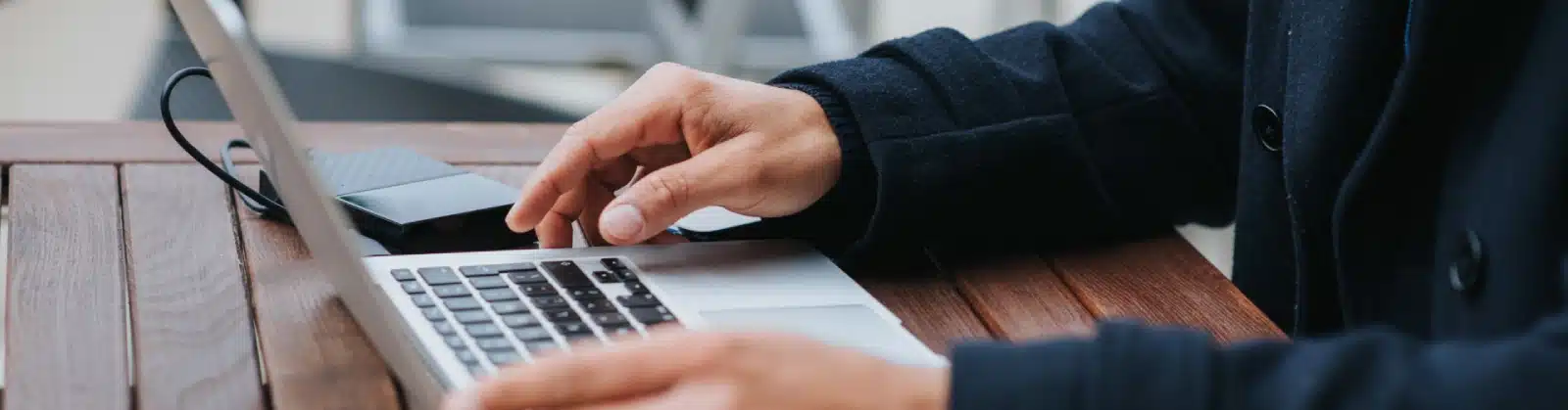 Professional person typing on laptop computer at wooden desk in modern office