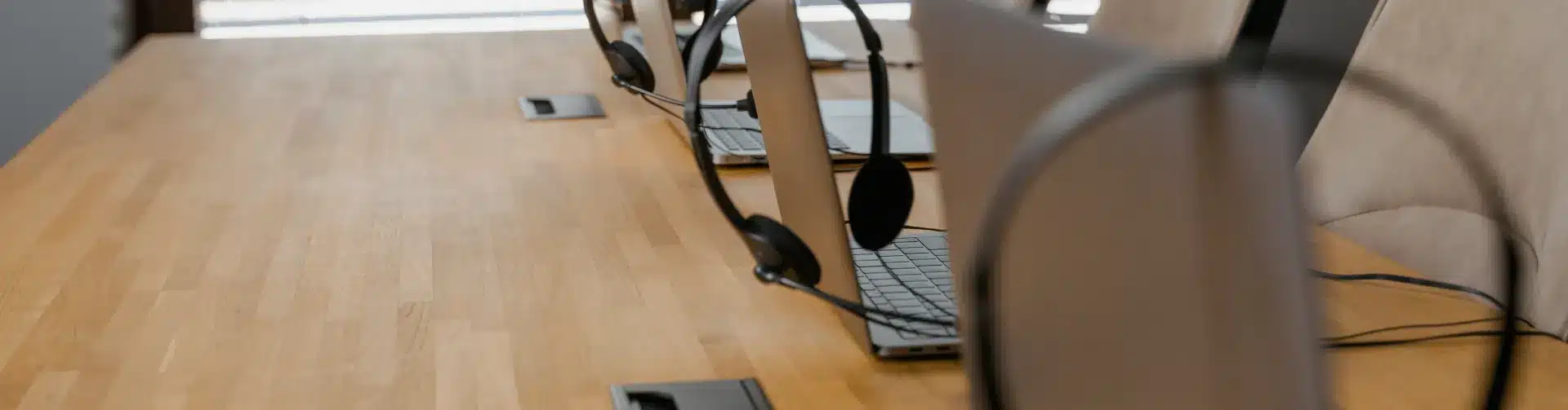 Modern conference room with wooden table, laptops, headsets and professional lighting