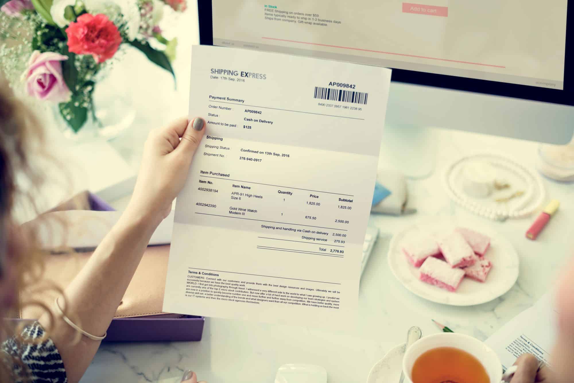 Woman at a computer looking at an invoice while shopping online