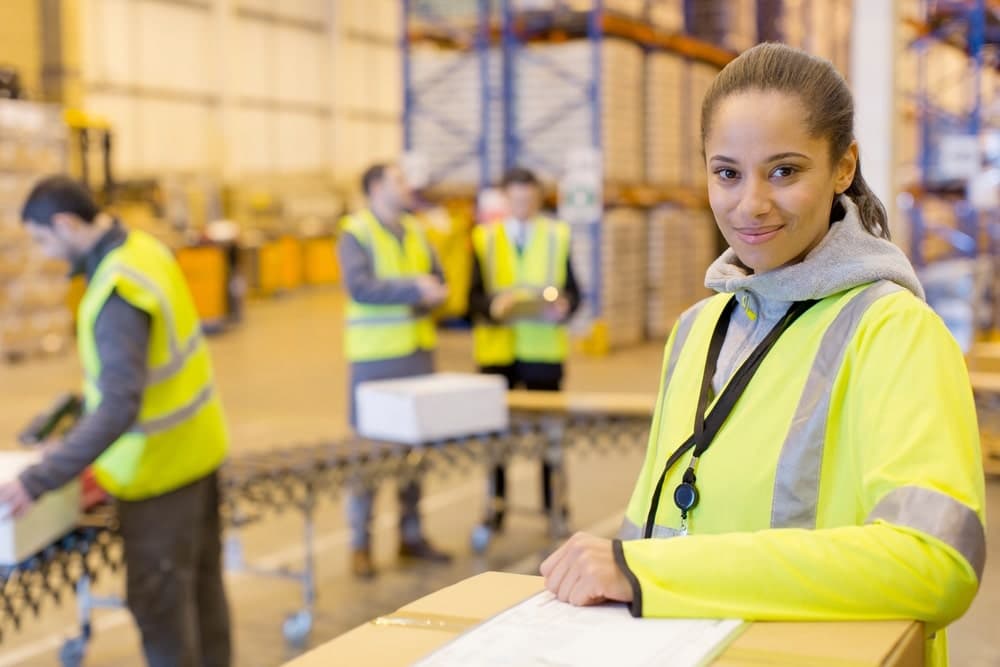 Warehouse worker in the line of a conveyor belt carrying boxes