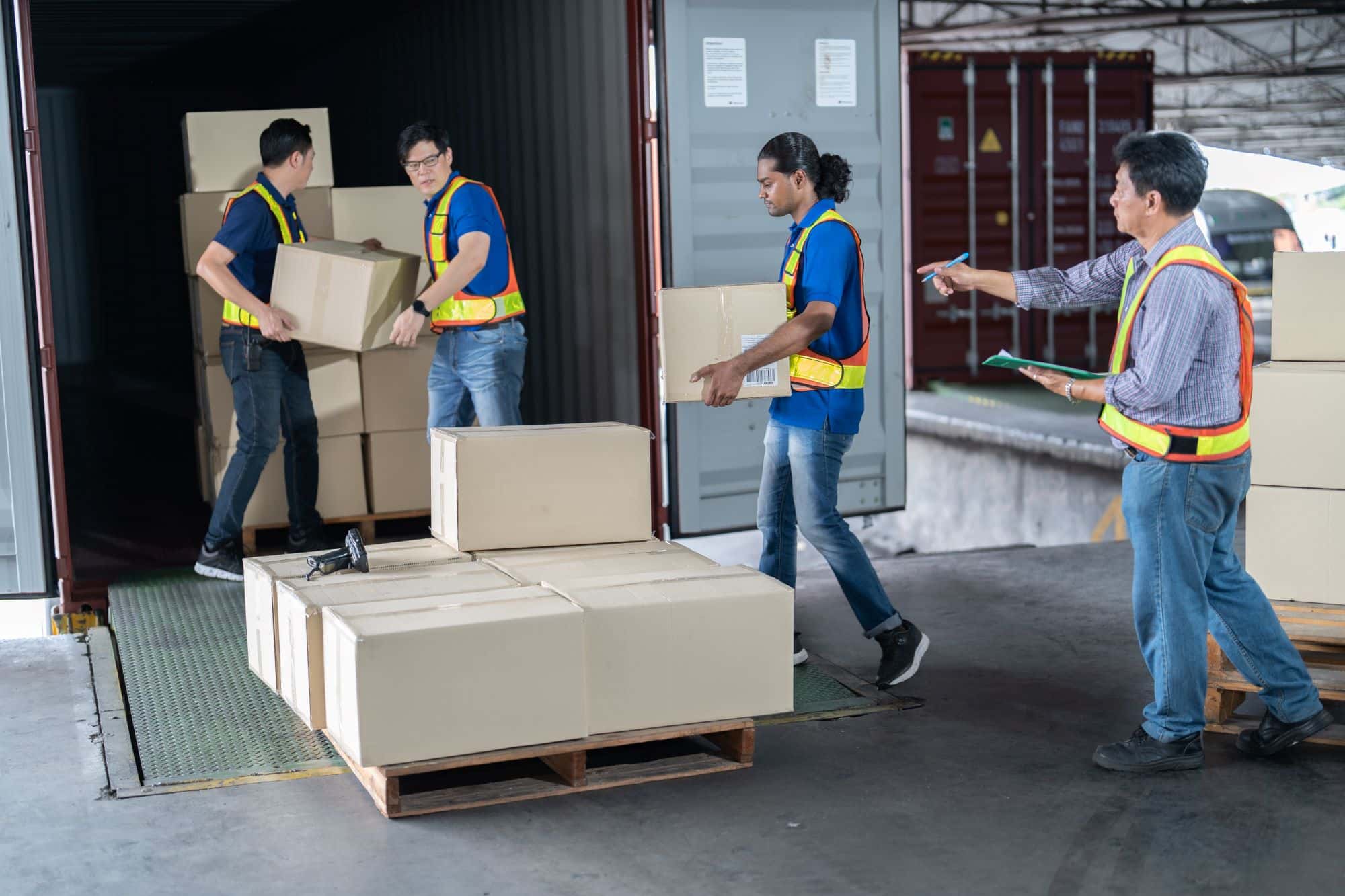 Four warehouse workers opening shipping container doors