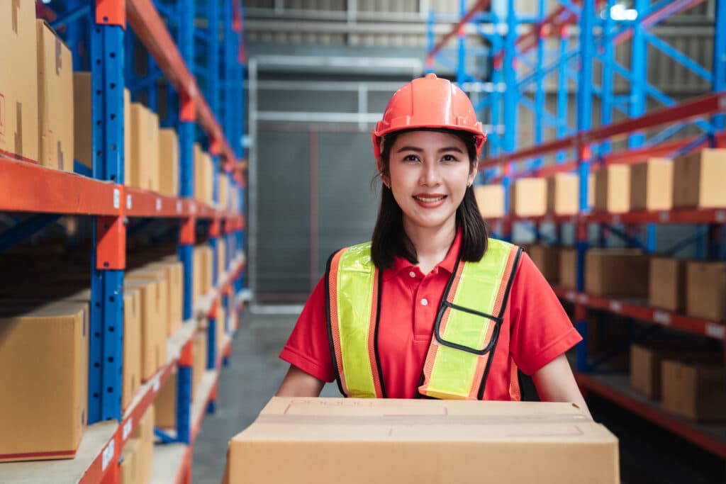 Warehouse worker holding a box with warehouse shelving in the background