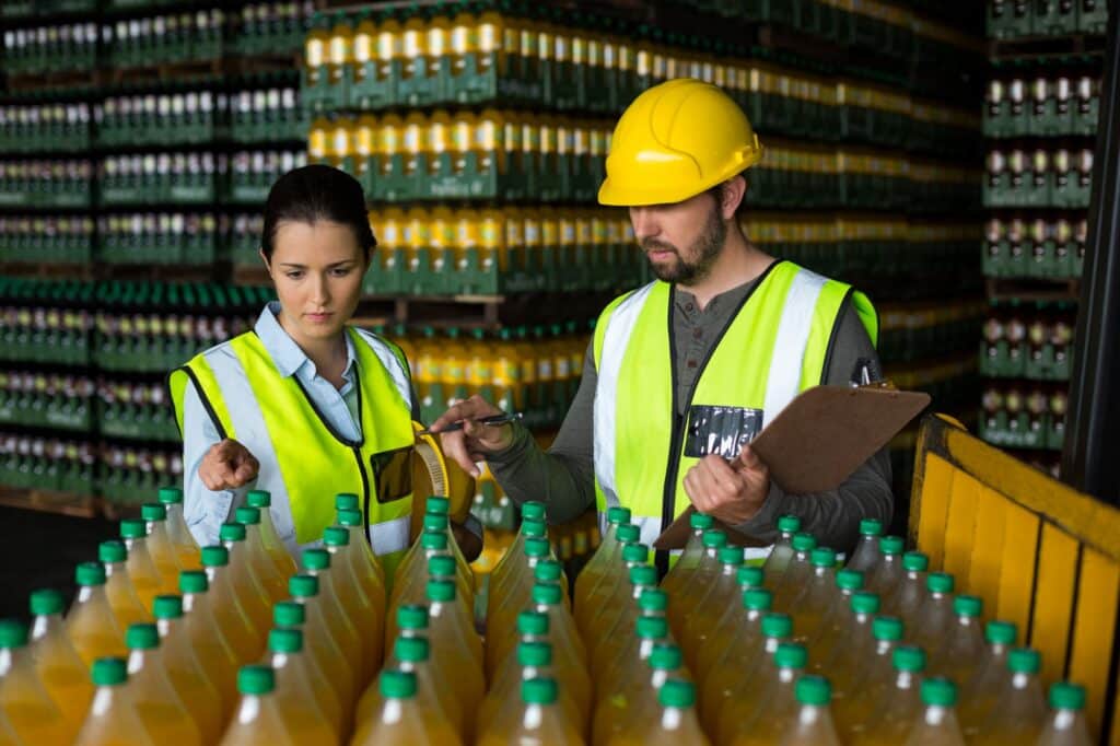 Two factory workers inspection juice bottles for quality control