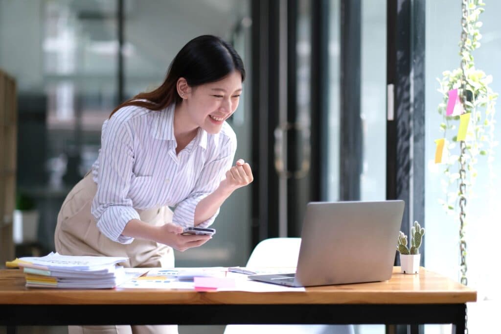 Woman looking at a laptop showing excitement with what she is seeing on the computer screen