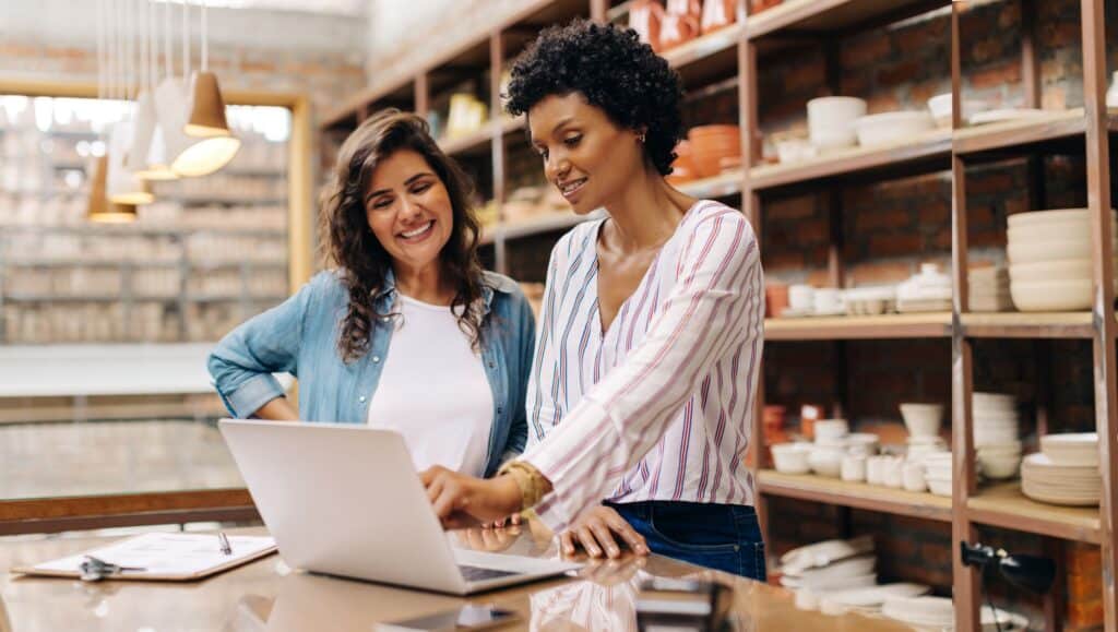 Two women looking at a computer in a pottery shop