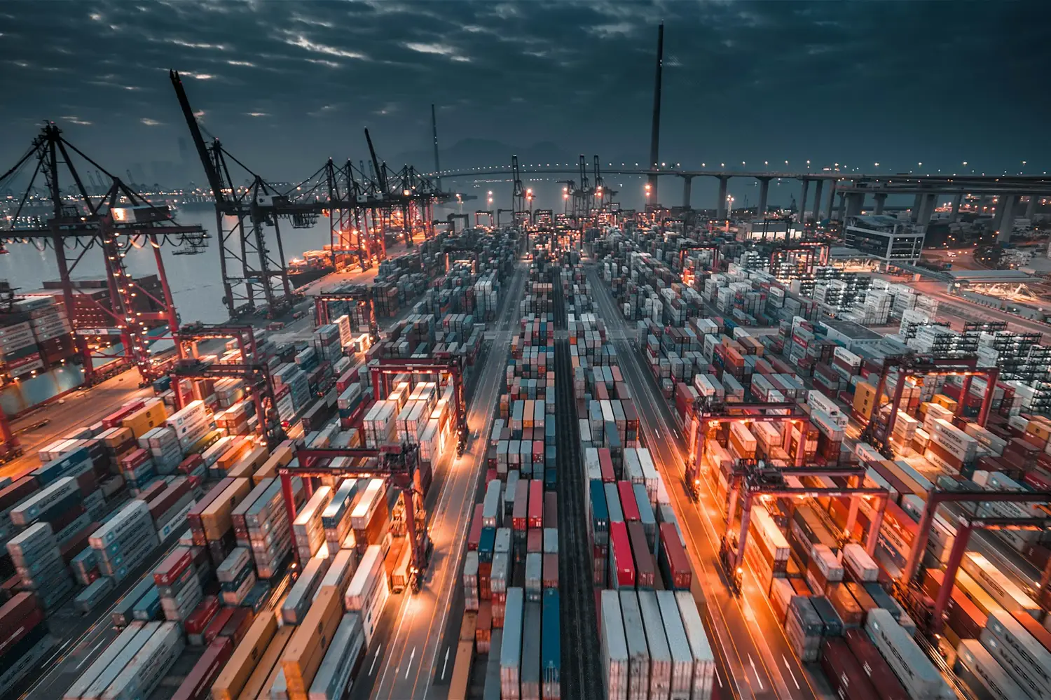 Container port with stacked containers and cranes at dusk
