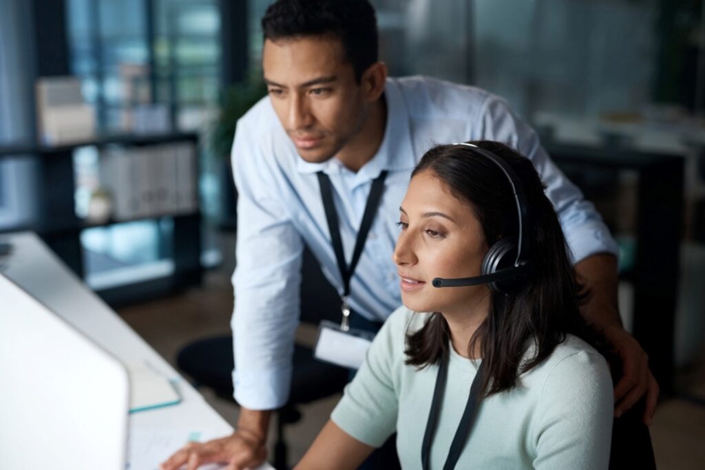 a person working at a computer asking a manager a question