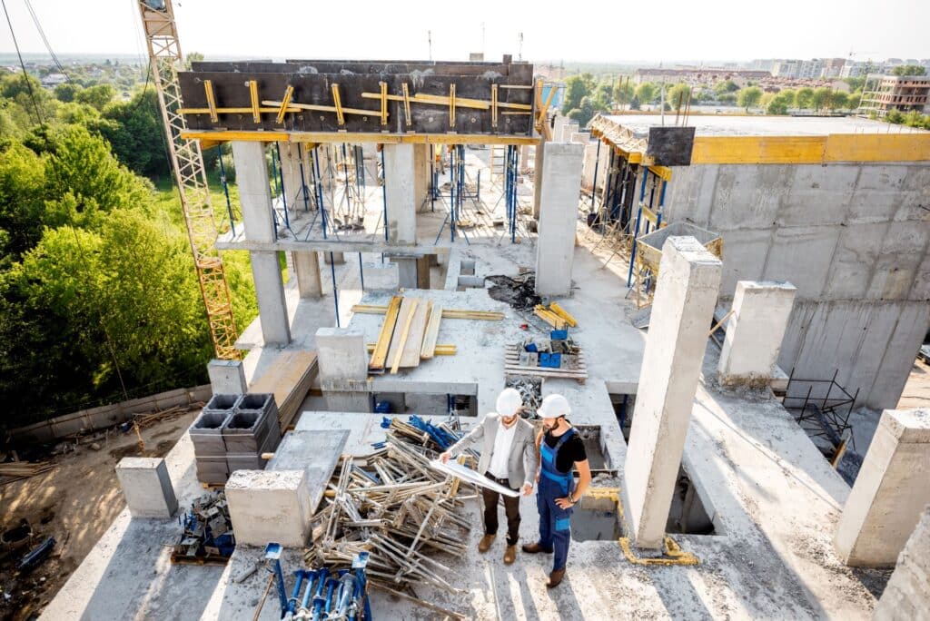 engineer and construction worker reviewing building plans at building site