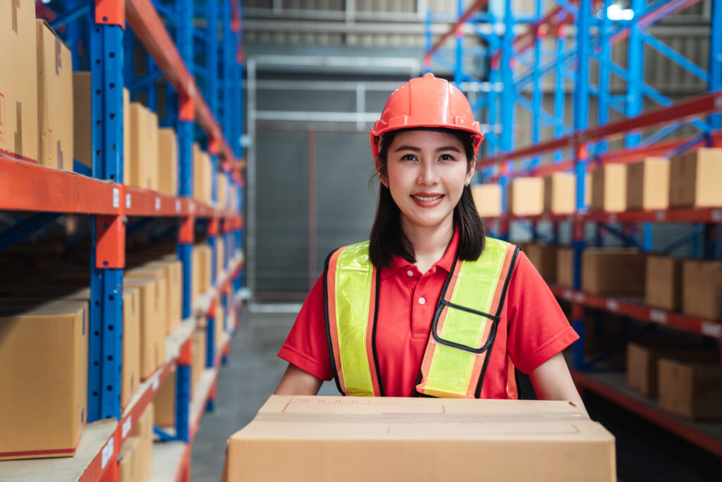 warehouse worker holding a box with warehouse shelving in the background